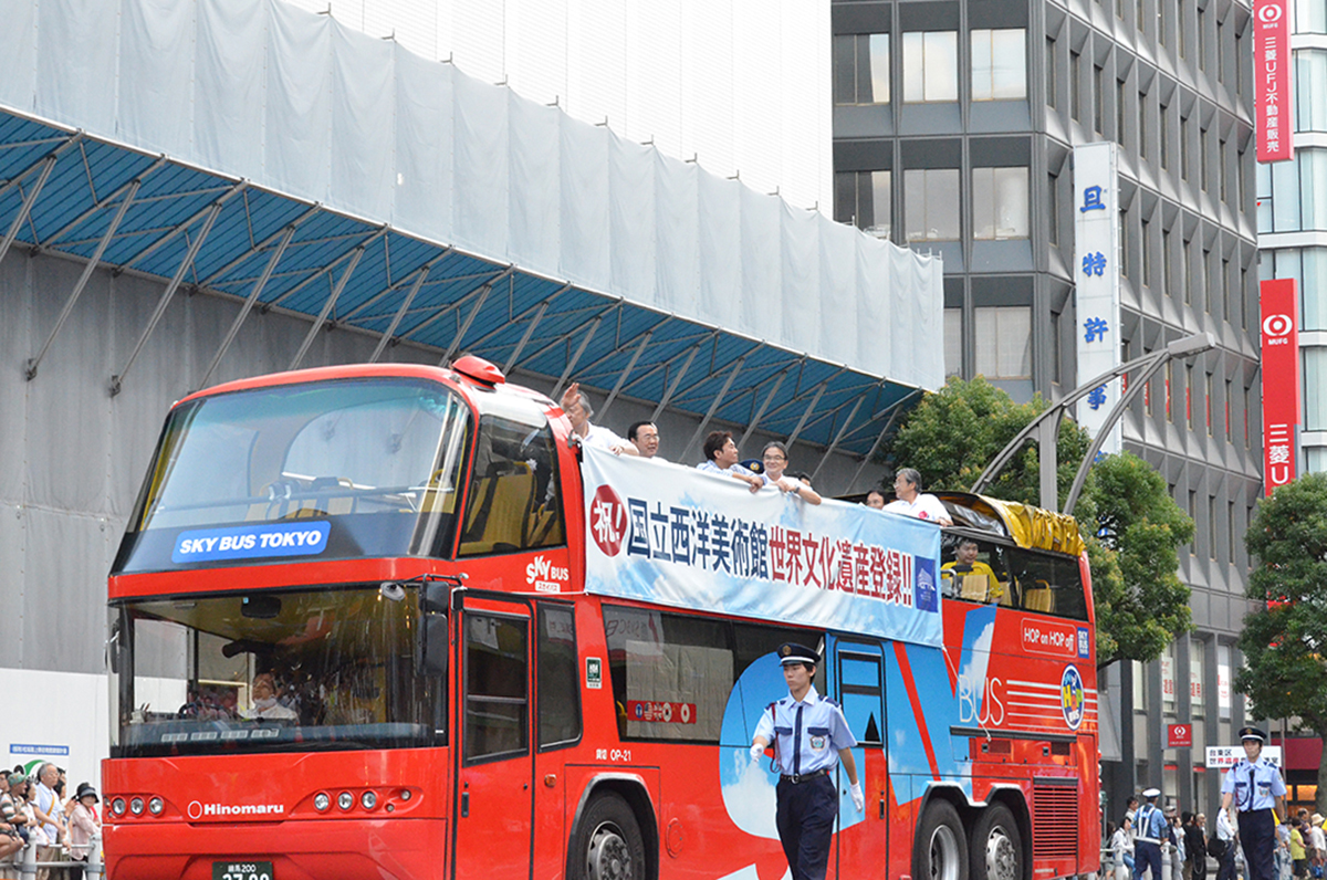 オープンバスから沿道の皆さまへ手を振る関係者